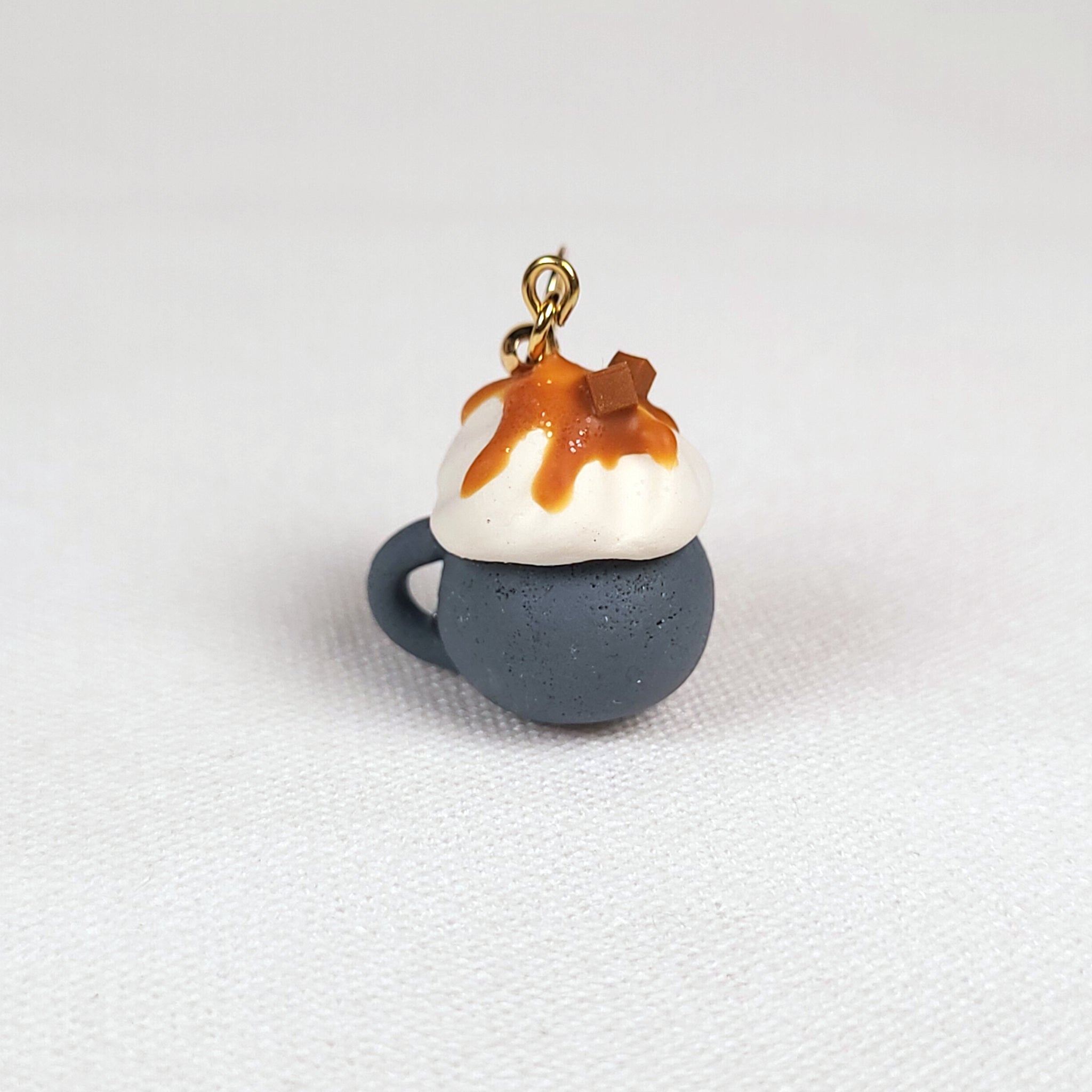Earrings shaped like small coffee mugs with whipped cream and caramel sauce on top
